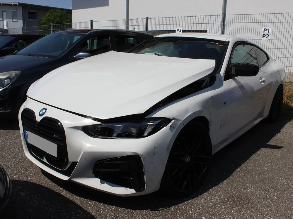 Weißer BMW 4er Coupé mit verschobener Motorhaube und aufgerissenem Kotflügel vorne links