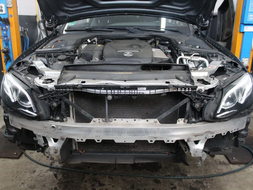 Mercedes mit abgebauter Front, verformtem Querträger und freiliegendem Kühler